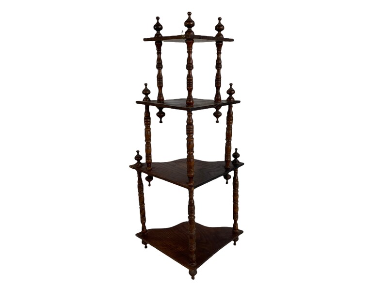 May include: A dark brown wooden corner shelf unit with three tiers. Each tier has a curved edge and is supported by four turned wooden posts with finials.
