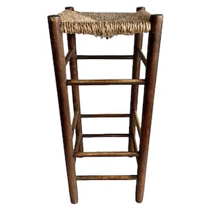 May include: A wooden stool with a woven straw seat and three shelves. The stool is dark brown and has a rustic look.