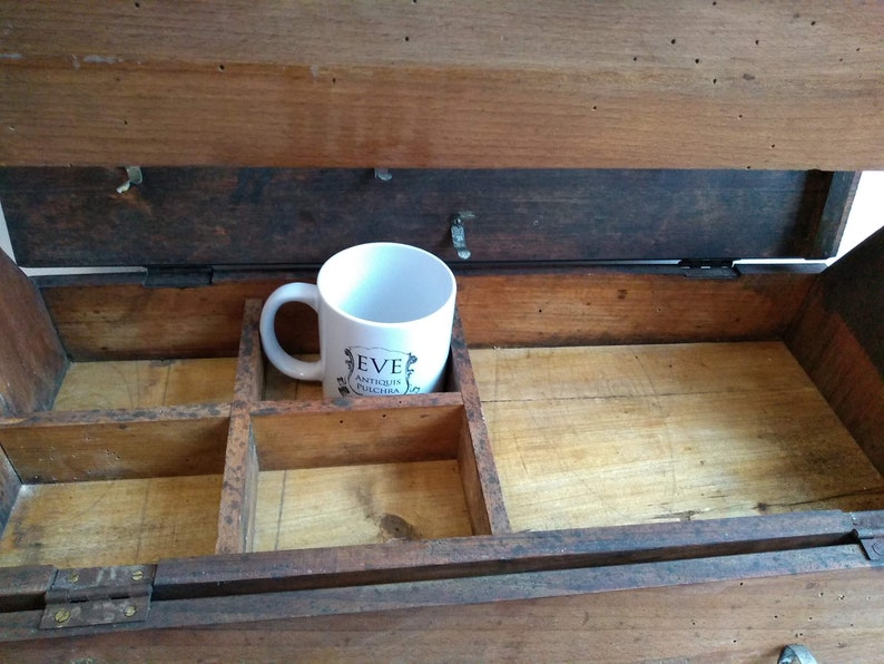 May include: A wooden box with a hinged lid and a divided interior. The box is open and a white ceramic mug with the text "Eve Antiquit&eacute;s Chic & Rare" is sitting inside.