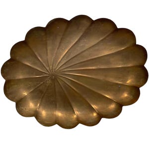 May include: A large, oval-shaped brass tray with a scalloped edge. The tray has a sunburst design and is made of a shiny, gold-colored metal.