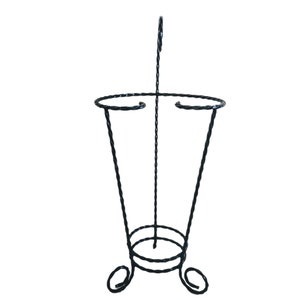 May include: Black metal umbrella stand with a twisted design and a round top. The stand has three legs that curl out at the bottom.