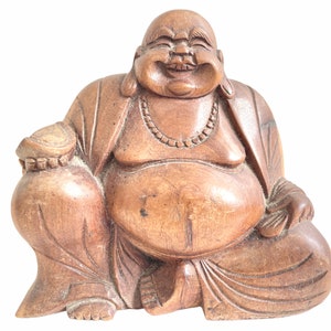 Può includere: Una statua di legno di un Buddha sorridente con la faccia rotonda, seduto a gambe incrociate e con una borsa in grembo. La statua è scolpita con dettagli intricati e ha un colore marrone caldo.