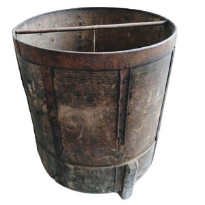 May include: A large, rustic wooden bucket with metal bands and a metal handle. The bucket is brown and has a worn, aged appearance.