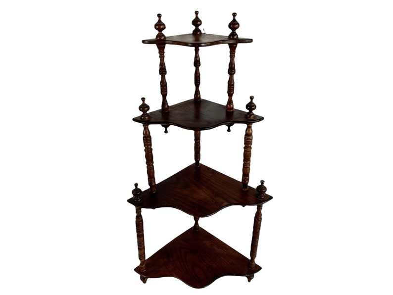 May include: A dark brown wooden corner shelf unit with three tiers. Each shelf has a curved edge and is supported by four turned wooden posts with decorative finials.