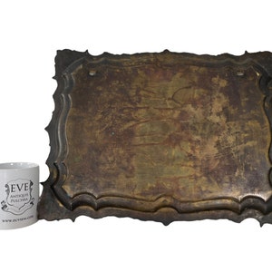 Puede incluir: Una placa grande, rectangular, ornamentada, de metal con un acabado desgastado, envejecido, marr&oacute;n. La placa tiene un borde decorativo festoneado.
