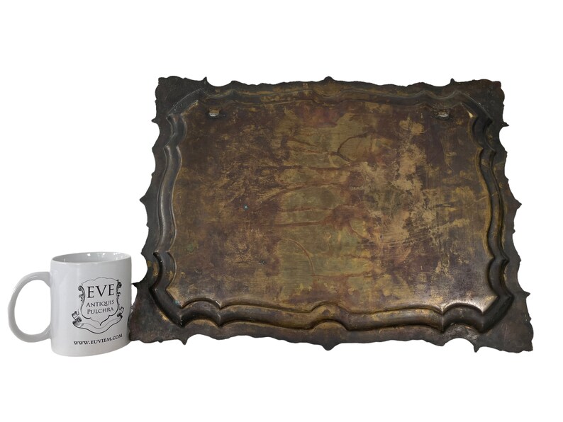Puede incluir: Una placa grande, rectangular, ornamentada, de metal con un acabado desgastado, envejecido, marr&oacute;n. La placa tiene un borde decorativo festoneado.
