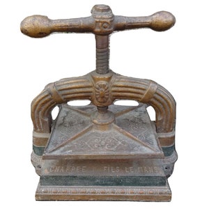 May include: Antique book press made of gold-toned metal with a decorative design and the inscription "Chappee Fils Le Mans".
