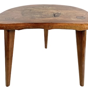 May include: A rustic wooden table with a half-moon shaped top and three legs. The table is made of natural wood with a rough, unfinished surface.