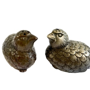 May include: A pair of silver bird salt and pepper shakers. The birds are detailed with feathers and have a realistic appearance.