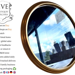 Peut inclure: Un miroir ovale dor&eacute; avec un cadre d&eacute;coratif. Le miroir refl&egrave;te un ciel bleu et un b&acirc;timent avec une enseigne qui indique "Antiquit&eacute;s Achat 07.69.28160.11".