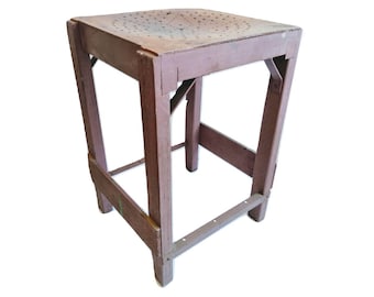 May include: A brown wooden stool with a square top and a metal base. The top has a pattern of holes.