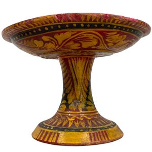 Könnte beinhalten: Eine handbemalte Holzschale mit einem roten und goldenen Blumendesign. Die Schale hat einen breiten, flachen Boden und einen hohen, schlanken Stiel.