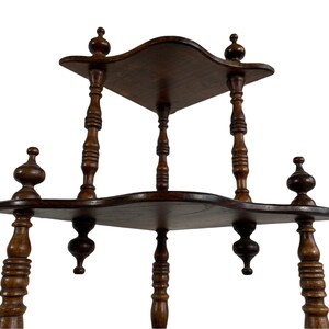 May include: A three-tiered wooden shelf with a scalloped edge and turned wooden legs. The shelf is made of dark wood and has a distressed finish.