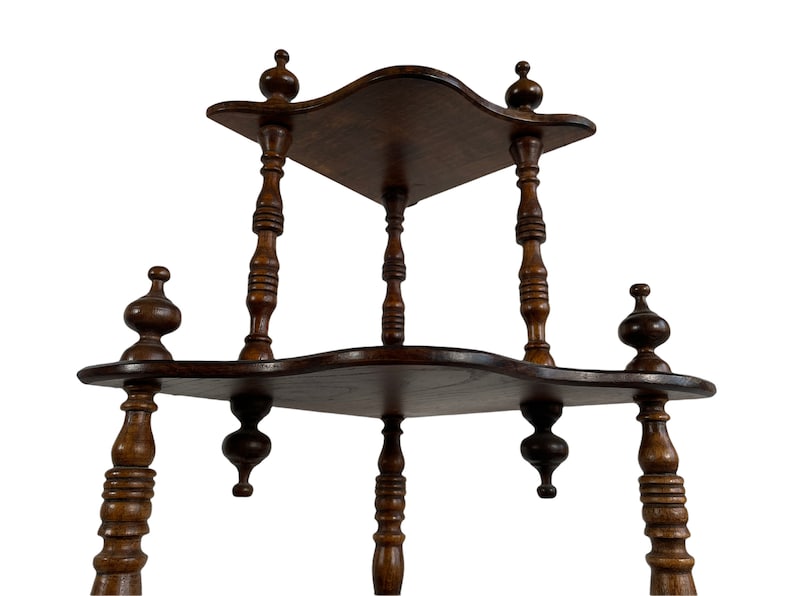 May include: A three-tiered wooden shelf with a scalloped edge and turned wooden legs. The shelf is made of dark wood and has a distressed finish.