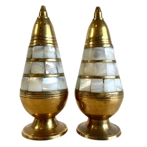 May include: A pair of gold metal salt and pepper shakers with a white mother of pearl inlay design.