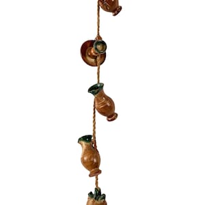 May include: A string of five brown and green ceramic vases hanging from a brown rope. The vases are all different shapes and sizes, and they have a rustic, handmade look.