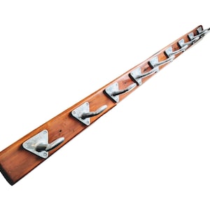 Può includere: Un appendiabiti in legno con otto ganci in metallo. L'appendiabiti è in legno naturale di colore marrone rossiccio. I ganci sono argentati e hanno una base triangolare.