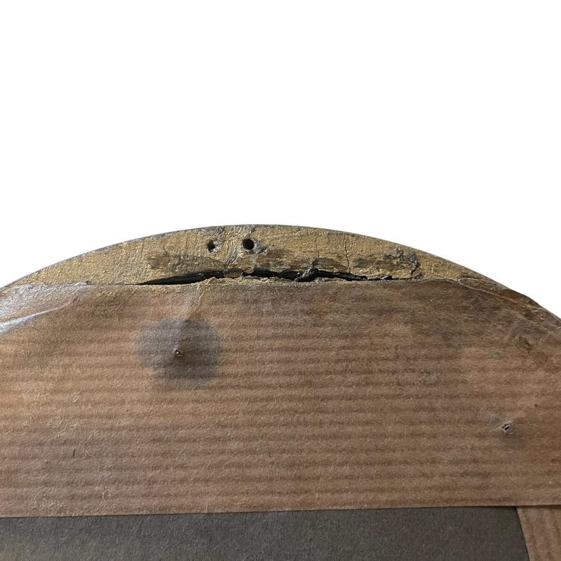 Puede incluir: Primer plano de la parte posterior de una obra de arte enmarcada en madera. El marco tiene un acabado pintado en oro y est&aacute; hecho de madera. La madera est&aacute; envejecida con grietas y agujeros. La obra de arte est&aacute; montada sobre un respaldo de madera.