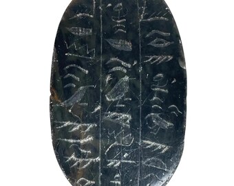May include: A dark green oval-shaped stone with ancient cuneiform script carved into its surface.