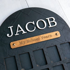 Wooden frame painted black with spots for school pictures. Reads "Jacob" and "My School Years"