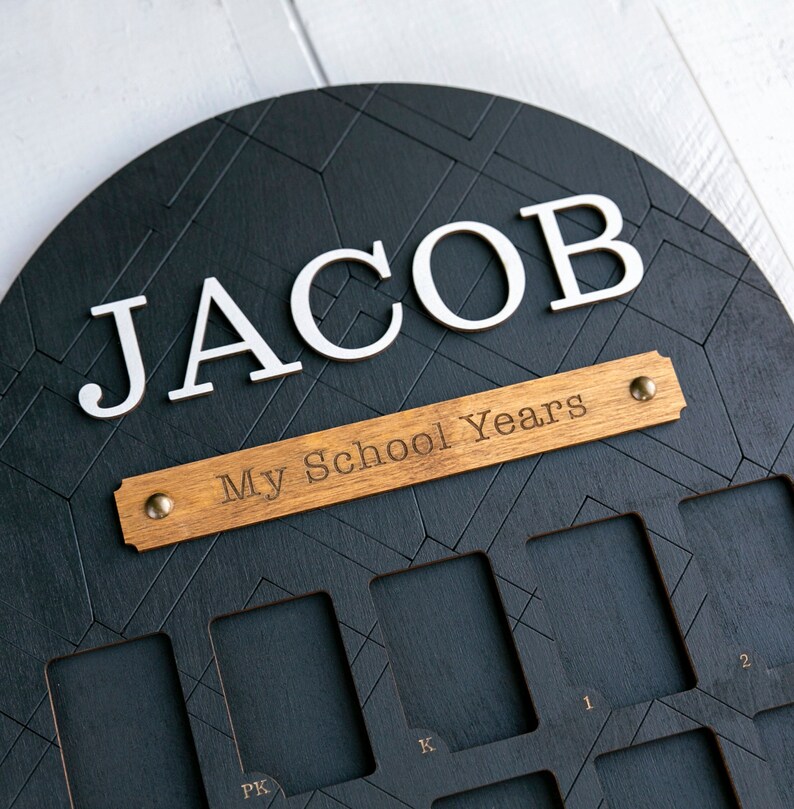 Wooden frame painted black with spots for school pictures. Reads "Jacob" and "My School Years"