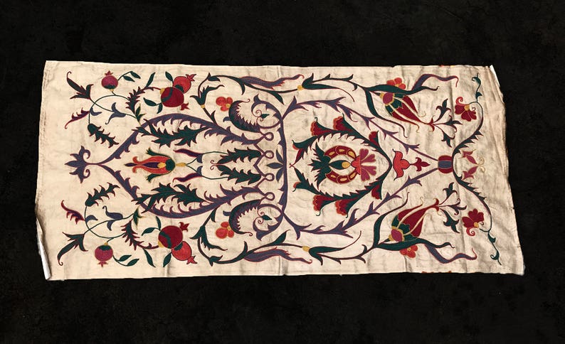May include: A white fabric panel with an intricate embroidered design featuring stylized flowers, leaves, and pomegranates in shades of red, green, purple, and gold.