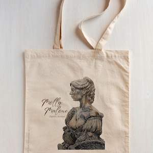 May include: Cream-colored tote bag featuring a detailed illustration of a statue of Molly Malone in Dublin, Ireland. The bag has long handles and the text "Molly Malone" in a script font. The bag is made of a natural fabric.