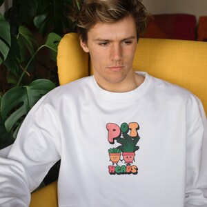May include: White sweatshirt with a graphic of two potted plants with faces and the text "POT HEADS" in colorful letters.