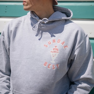 May include: A gray hoodie with a graphic of a sundae ice cream with the text "SUNDAE BEST" in pink.