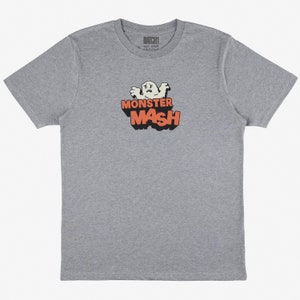 Può includere: Una t-shirt grigia melange con un fantasma dei cartoni animati e il testo "Monster Mash" in arancione.