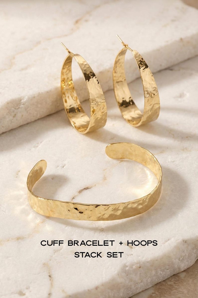 May include: A gold-coloured jewellery set featuring a cuff bracelet and two hoop earrings. The jewellery has a hammered texture. The text on the image reads "CUFF BRACELET + HOOPS STACK SET."