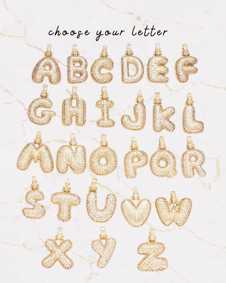Op de afbeelding: Gouden letterhangers, elk bezet met kleine, glinsterende steentjes. De hangers worden getoond tegen een achtergrond met marmer-effect. De tekst "choose your letter" staat er in sierlijke letters boven.