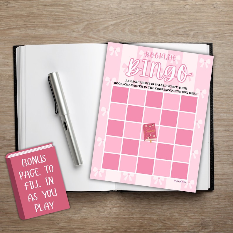 May include: A pink "Bookish Bingo" game card with a grid, bows, and the text "As each prompt is called write your book/character in the corresponding box here." A silver pen and a pink bonus page are also visible.