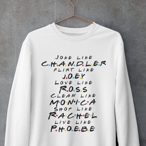 以下が含まれることがあります： 「Joke like Chandler, Flirt like Joey, Love like Ross, Clean like Monica, Shop like Rachel, Live like Phoebe」と黒で書かれたグラフィックプリントが施された白いスウェットシャツ。
