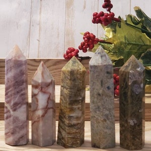 May include: Five polished stone points in various colors and patterns, labeled A through E. The points are arranged in a row on a wooden surface.