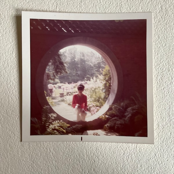 Vernacular Photography, woman sitting in a moon gate, circular door frame, excellent composition, tourist, color photo, old photo snapshot