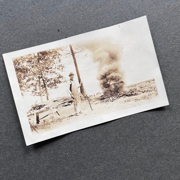 Vernacular Photography, Man burning debris, fire, smoke photo, found image, snapshot of man in vintage workwear, tending a fire