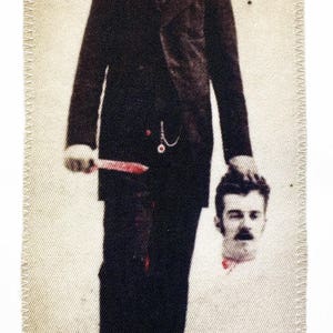 Könnte beinhalten: Ein Mann im Anzug hält einen abgetrennten Kopf in der Hand. Der Mann hält ein Messer in der anderen Hand. Der Hintergrund ist hellbeige.