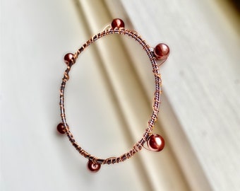 Copper wire and bronze pearls wrapped around lavender bangle with faint green glitter