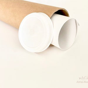 May include: A white print is rolled inside a brown cardboard tube, with a white plastic cap beside it. The image is set against a light cream background. The text "Art by Anna Alvarado" is in the bottom right corner.