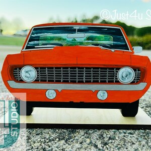 May include: A red vintage muscle car model with a black grille and chrome accents. The car is sitting on a wooden base. &copy;Just4U Studio