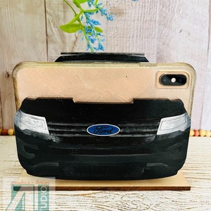 Pu&ograve; includere: Un supporto per telefono nero a forma di SUV Ford con una base in legno. Il supporto &egrave; progettato per tenere uno smartphone in posizione verticale. Il supporto per telefono &egrave; un ottimo modo per esporre il tuo telefono e tenerlo a portata di mano.
