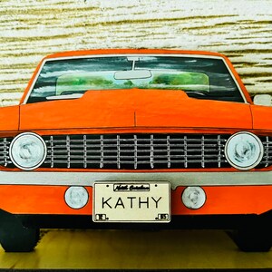 May include: A red vintage car with a black grille and chrome accents. The car has a personalized license plate that reads "Kathy".