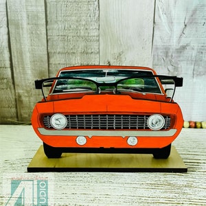 May include: A red vintage car with a black grill and headlights. The car is on a wooden base and has a pair of glasses on top of the windshield. The text "Just4u Studio" is visible in the upper right corner of the image.