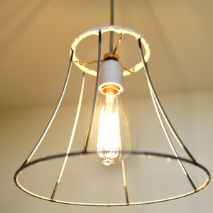 May include: A black wire lampshade with a white fabric lining and a clear light bulb. The lampshade is hanging from the ceiling.