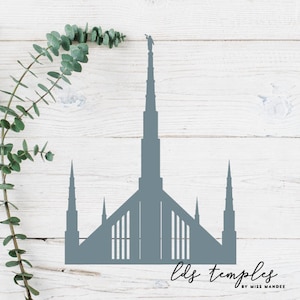 May include: A gray silhouette of a Mormon temple with a spire on a white wood background. The text "lds temples by miss mandee" is at the bottom of the image.