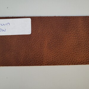 May include: A close-up of a brown leather swatch with a white label that says "Brown Cow".