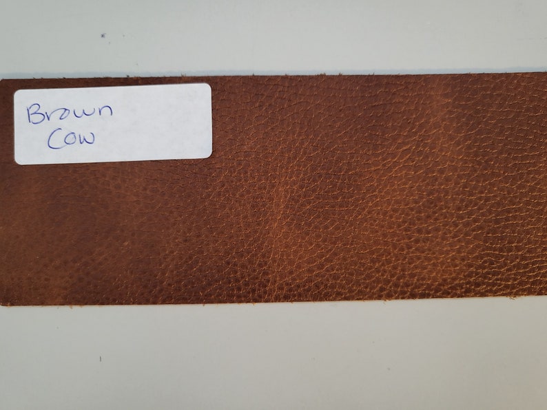 May include: A close-up of a brown leather swatch with a white label that says "Brown Cow".