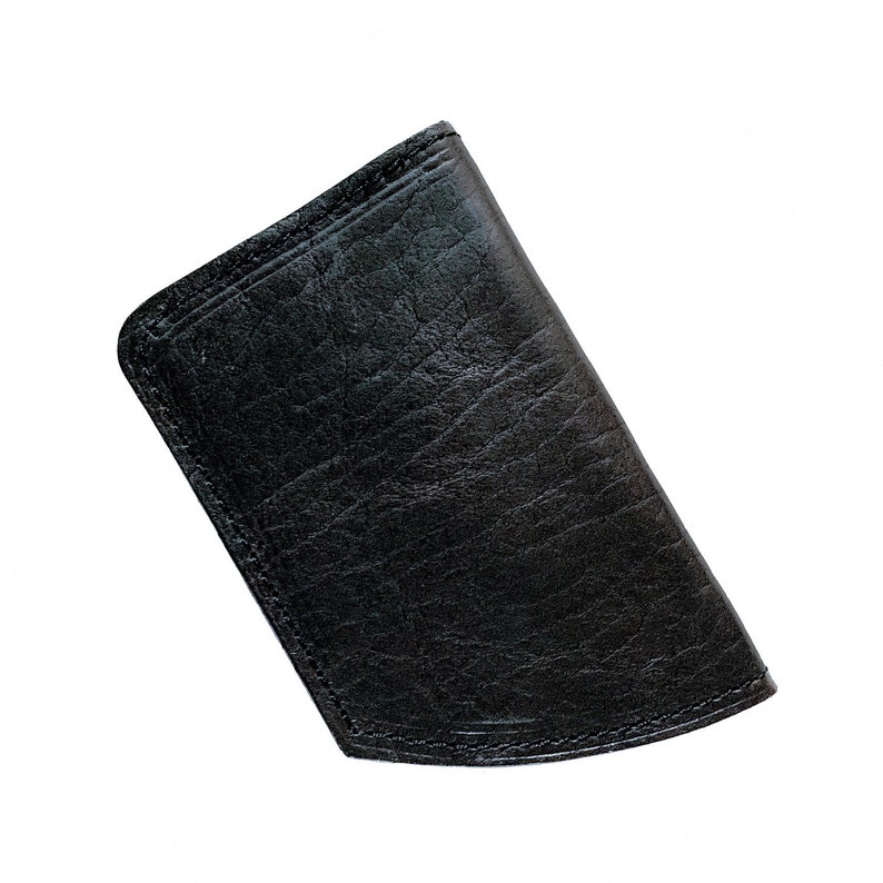 May include: A black leather wallet with a textured finish. The wallet is rectangular with curved corners and appears to be closed. Stitching is visible along the edges.