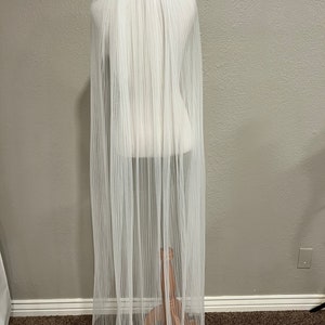 May include: A white tulle wedding veil with a pleated design. The veil is displayed on a mannequin.